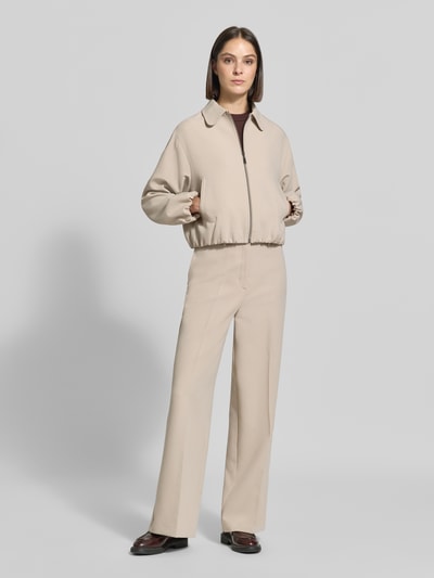 Frauenmodel trägt Straight Fit Hose mit Viskose-Anteil von MORE & MORE in Beige, elastischer Material-Mix, Bügelfalten, Ganzkörperansicht von vorne.
