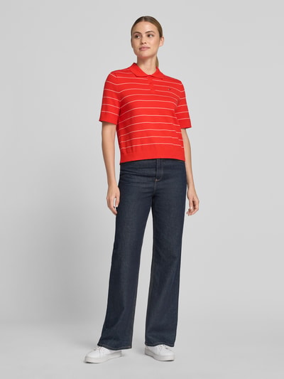 Frauenmodel trägt Regular Fit Pullover aus reiner Baumwolle mit Polokragen von Tommy Hilfiger in Rot mit weißen Streifen, Damen Pullover, Ganzkörperansicht von vorne.