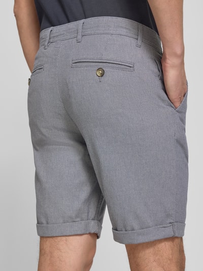 Männermodel trägt Slim Fit Chinoshorts aus Baumwoll-Mix Modell 'LUTON' von SELECTED HOMME in Grau, feine Webstruktur, Ganzkörperansicht Rückansicht.