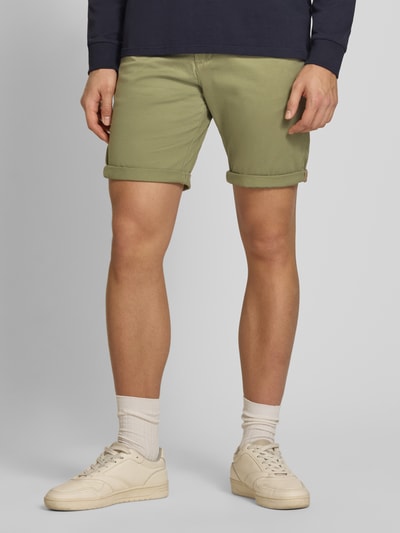 Männermodel draagt Regular Fit Shorts met steekzakken model 'BOWIE' van Jack & Jones, mix van katoen en elastaan, regular fit, omslag, bandwijdte maat M 43 cm, binnenbeenlengte maat M 26 cm, olijfgroen, gladde textuur. Detailaufnahme.