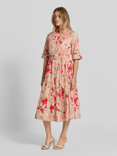 Frauenmodel trägt Hemdblusenkleid aus Reine Viskose, Modell 'FALDINE' von Soyaconcept mit Knopfleiste, Bindegürtel, 3/4-Arm, taillierte Passform, Midikleid, Umlegekragen, in bunten Beige- und Rottönen, fließende Textur, Ganzkörperansicht von vorne.
