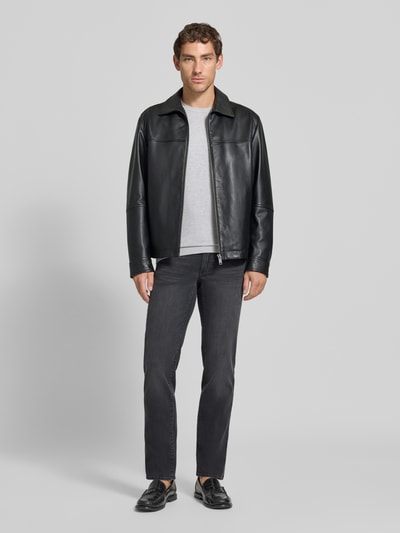 Männermodel trägt schwarze Straight Fit Jeans aus Baumwoll-Mix Modell 'Cadiz' von Brax, graues Shirt und schwarze Jacke, Ganzkörperansicht von vorne, Herren Straight Fit Jeans von Brax.