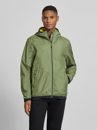 Männermodel trägt Jacke mit Kapuze Modell 'KOS' von Killtec in Olivgrün mit Reißverschluss, Label-Patch, Seitliche Reißverschlusstaschen, Elastische Ärmelabschlüsse, Gerader-Schnitt, Ganzkörperansicht von vorne. Rückenlänge 74 cm, Schulterbreite 52 cm, Brustweite 58 cm, Ärmellänge 68 cm, Größe M.