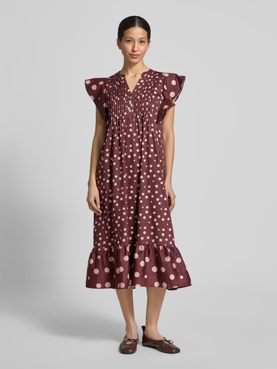Frauenmodel trägt Relaxed Fit Midikleid mit gelegten Falten von Christian Berg Woman in Braun mit Rosa Punkten, Reine Baumwolle, Tunika-Ausschnitt, Kappärmel, Knopfleiste, Ganzkörperansicht von vorne. Rückenlänge 117 cm, Brustweite 32 cm, Ärmellänge 15 cm bei Größe 36.