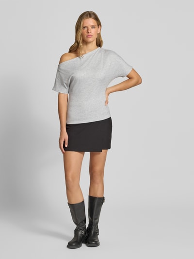 Frauenmodel trägt Regular Fit T-Shirt mit Viskose-Anteil Modell 'SILLY' von ONLY in Hellgrau, kombiniert mit kurzem schwarzen Rock und schwarzen Stiefeln, Ganzkörperansicht von vorne. Damen T-Shirt von ONLY.