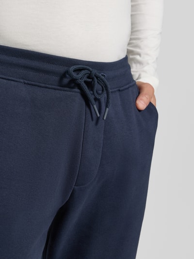 Männermodel trägt Straight Fit Jogginghose aus Baumwoll-Mix von MCNEAL in Dunkelblau, sichtbare Eingrifftaschen, Nahaufnahme Oberkörper. Herren Jogginghose, elastische Abschlüsse, Innenbeinlänge bei Größe M: 77 cm.