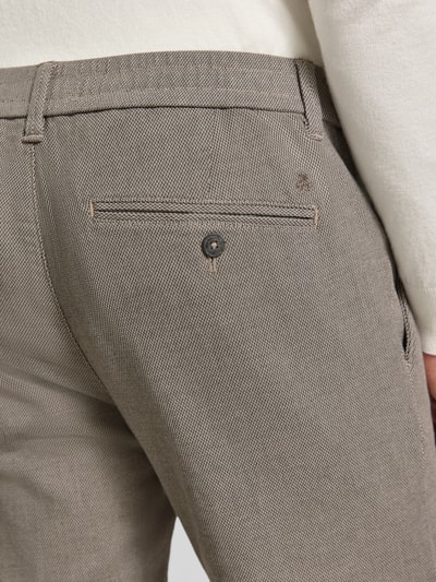 Mężczyznamodel nosi Regular Fit Schmale Hose aus Baumwoll-Mix Modell 'Stig Jogger' von Marc O'Polo, spodnie z mieszanki bawełny, szaro-beżowe, widoczna tylna kieszeń z guzikiem, Herren Schmale Hose von Marc O'Polo, zbliżenie tylnej części.