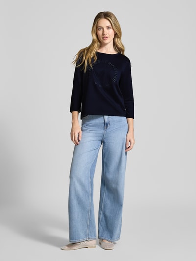 Vrouwenmodel draagt Relaxed Fit Sweatshirt met viscose-aandeel model 'Emblem' van monari, ronde hals, 7/8-mouw, donkerblauw, rechte pasvorm, lichte jeans, kleurrijk contrast, geheel lichaam van voren