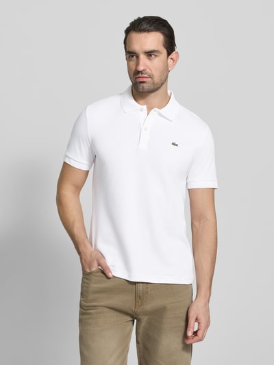 Männermodel trägt Regular Fit Poloshirt aus reiner Baumwolle von Lacoste, Optik: Unifarben, Logo-Detail, Ganzkörperansicht von vorne.