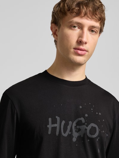 Männermodel trägt Regular Fit T-Shirt aus reiner Baumwolle Modell 'NIEROFIX_U261' von HUGO, Optik: Unifarben, Motiv-Print, Nahaufnahme Oberkörper.