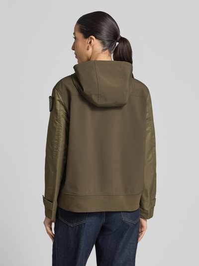Frauenmodel trägt Regular Fit Jacke mit Logo-Detail Modell 'Marcela' von Blauer Usa in Olivgrün mit Kapuze und Eingrifftaschen, Rückenlänge bei Größe S: 60 cm, Schulterbreite: 43 cm, Brustweite: 47 cm, Ärmellänge: 59 cm, Ganzkörperansicht Rückansicht.