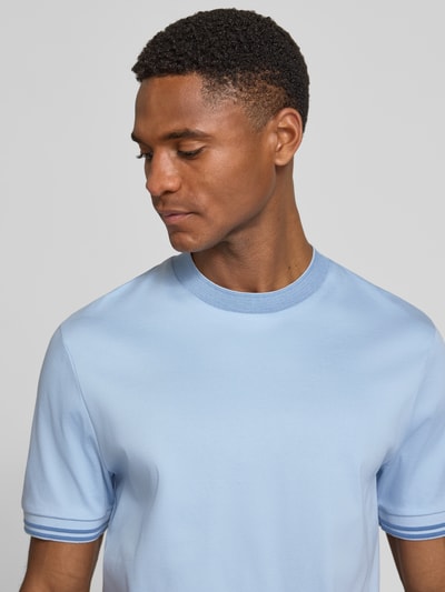 Mannenmodel draagt lichtblauw slim fit T-shirt van pure katoen, model 'H-TESSLER 238' van BOSS met contrasterende stiksels, unie kleur, ronde hals en korte mouw, detailopname bovenlichaam.