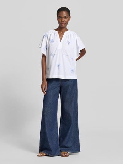 Frauenmodel trägt Relaxed Fit Tunikabluse mit Stitchings von Oui aus weißer Baumwolle mit blauen Nähten, Allover-Look, V-Ausschnitt, Ganzkörperansicht von vorne.