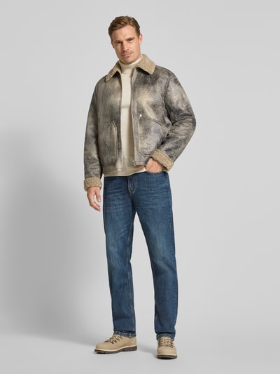 Männermodel trägt Jacke mit Kentkragen Modell 'LERON' von DRYKORN, graubeige Töne, Teddyfellkragen, gerade Form, Eingrifftaschen, Ganzkörperansicht von vorne.