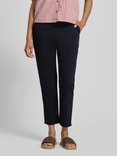 Frauenmodel trägt Chino mit Fransensaum von Marc Cain aus dunkelblauem Baumwoll-Mix mit Stretch, Slim Fit, Nahaufnahme Oberkörper bis Fuß.