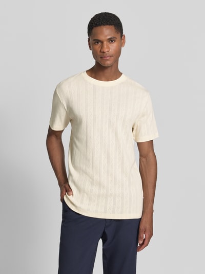 Männermodel trägt T-Shirt in Jaquard-Strick mit Rundhalsausschnitt von Lindbergh in Creme mit Ton-in-Ton Muster, Regular Fit, Ganzkörperansicht von vorne.