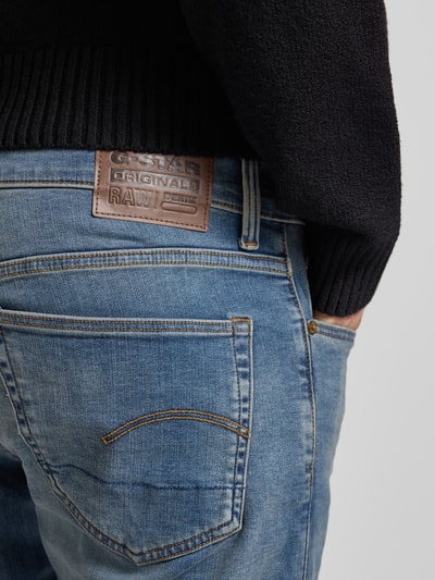 Mężczyznamodel nosi Jeansy z 5 kieszeniami od G-Star Raw w niebieskim kolorze, mieszanka bawełny, krój slim fit, detal z guzikiem i zamkiem błyskawicznym, tył, zbliżenie tylnej kieszeni, długość wewnętrzna nogawki 81 cm, szerokość w pasie 45 cm, rozmiar 32/32.