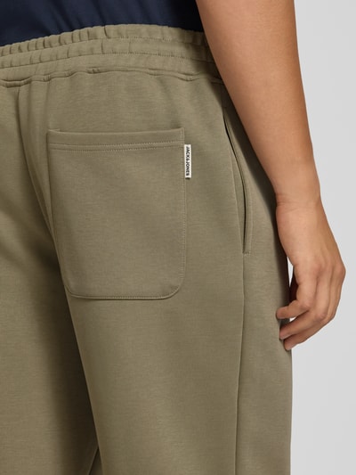 Männermodel trägt Straight Fit Sweatpants mit elastischem Bund von JACK & JONES in Olivgrün, Baumwoll-Mix, Eingrifftaschen, Detailaufnahme Rückansicht.