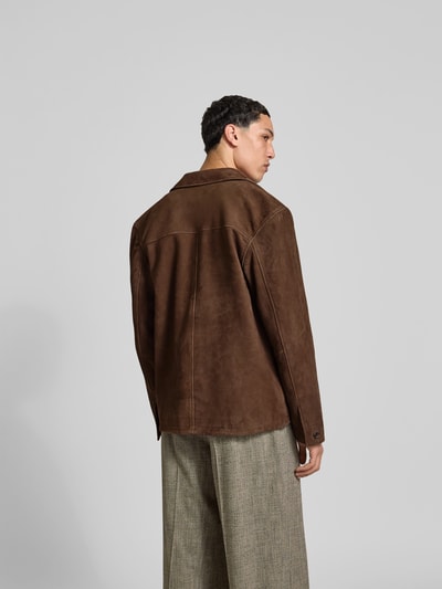 Männermodel trägt Lederjacke aus echtem Ziegenleder von Officine Générale, braun, Regular-Fit, Reverskragen, Pattentaschen, durchgängige Knopfleiste, Ganzkörperansicht Rückansicht.