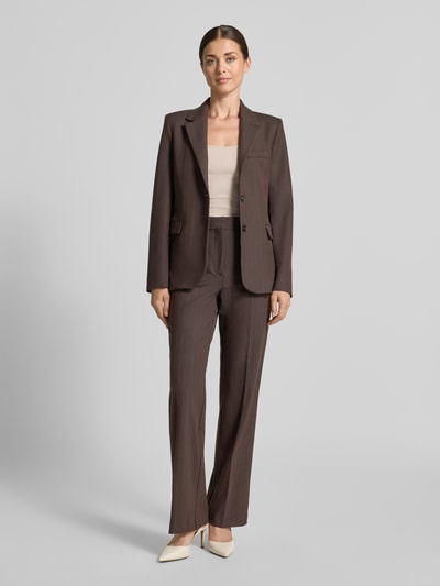 Frauenmodel trägt Regular Fit Blazer mit Viskose-Anteil Modell 'Bergen' von MANGO in Braun, elastischer Stoff, Reverskragen, Pattentaschen, Zwei-Knopfleiste, glatte Struktur, Ganzkörperansicht von vorne.