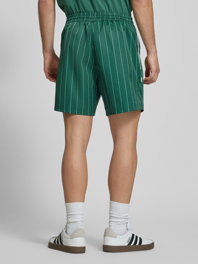 Mannenmodel draagt Shorts mit Streifenmuster und elastischem Bund van BLKVIS in regular fit, streepmotief, labelstitching, elastische band, bandwijdte maat M 36 cm, binnenbeenlengte 15 cm, groene tinten, rechte lijnen, gladde textuur. Ganzkörperansicht Rückansicht.