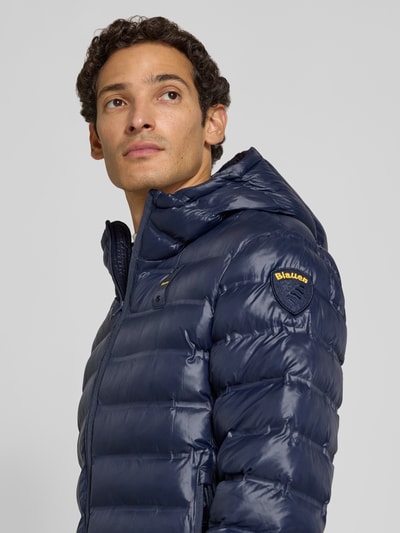 Männermodel trägt dunkelblaue Steppjacke mit Kapuze und Zweiwege-Reißverschluss, Modell 'CHARLES' von Blauer USA, Nahaufnahme Oberkörper.