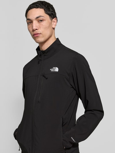 Männermodel trägt Jacke mit Stehkragen und Logo von The North Face, mieszanka materiałów z dodatkiem streczu, krój regular fit, stójka, zamek błyskawiczny, logo, kieszenie zapinane na zamek błyskawiczny, długość tyłu w rozmiarze M: 71 cm, szerokość ramion w rozmiarze M: 46 cm, szerokość klatki piersiowej w rozmiarze M: 56 cm, długość rękawów w rozmiarze M: 58 cm, kolor czarny, gładka faktura, nahaufnahme górnej części ciała
