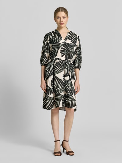 Frauenmodel trägt Knielanges Kleid aus Viskose-Mix mit Tunika-Ausschnitt von Christian Berg Woman Selection, Floraler Allover-Print, taillierte Passform, Halbarm, schwarz-weiß, glatte Textur, Ganzkörperansicht von vorne.
