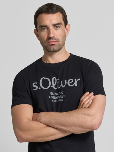 Męski model nosi Regular Fit T-Shirt aus reiner Baumwolle Modell 'BASIC TEE BIG LOGO' von s.Oliver RED LABEL, czarny kolor, nadruk, gładka tekstura, Nahaufnahme Oberkörper.