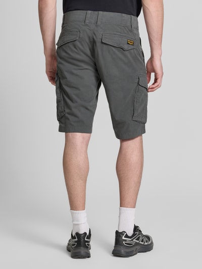 Männermodel trägt Tapered Fit Cargo Bermudas mit Pattentaschen Modell 'Nordrop' von PME Legend in grijs katoenmix met stretch, klepzakken, steekzakken, labelpatch op de achterkant, strookzak aan de achterkant, knoop- en ritssluiting, heren cargo, ganzkörperansicht rückansicht.