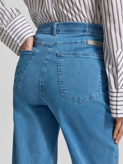 Kobiece modelka nosi Flared Fit Jeans mit Eingrifftaschen Modell 'Laura' von Raphaela By Brax, mieszanka bawełny elastycznej, jasnoniebieski kolor, wpuszczane kieszenie, kieszenie z tyłu, zapięcie na guzik i zamek błyskawiczny, szerokość w rozmiarze 36: 44 cm, długość wewnętrzna nogawki w rozmiarze 36: 79 cm, detaliczne ujęcie tylnej części ciała.