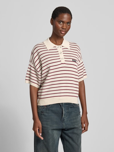 Frauenmodel trägt Relaxed Poloshirt mit Woll-Anteil von ROTATE im Modal-Mix, Strick-Optik, Streifenmuster, Kurzärmelig, Relaxed-Fit, Ganzkörperansicht von vorne.