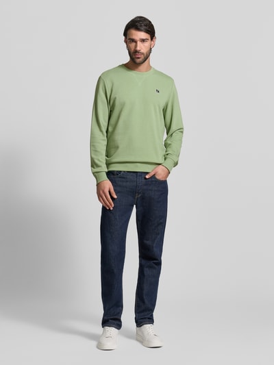 Mannelijk model draagt Regular Fit Sweatshirt aus Baumwoll-Mix van s.Oliver RED LABEL in effen lichtgroen, ronde hals, lange mouw, geribde boorden, sweattricot, logo-stiksel, ganzkörperaanzicht van voren.
