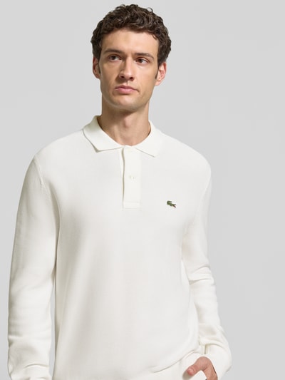 Männermodel trägt Regular Fit Poloshirt aus reiner Baumwolle von Lacoste in Cremeweiß mit glatter Textur, Nahaufnahme Oberkörper, Herren Poloshirt von Lacoste.