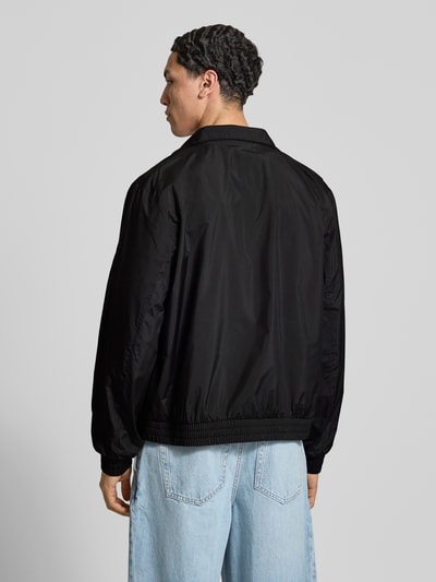 Männermodel trägt Trainingsjacke mit Logo und Stehkragen van Calvin Klein Jeans in zwart met regular fit en rits, rugaanzicht