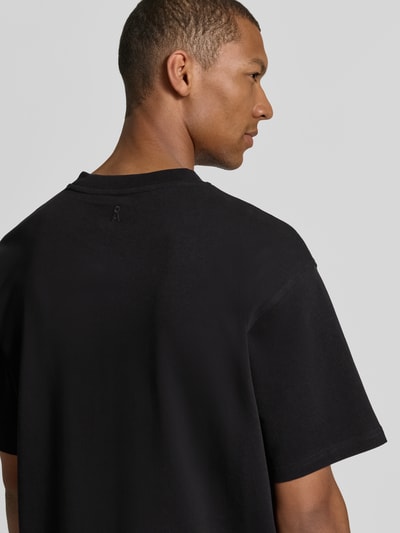 Männermodel trägt schwarzes Relaxed Fit T-Shirt aus reiner Baumwolle Modell 'MAARKOS' von ARMEDANGELS, Herren T-Shirt, Ganzkörperansicht Rückansicht.