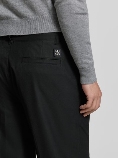 Männermodel trägt Weite Hos mit Viskose-Anteil Modell 'RIKO261' van HUGO in zwart, regular fit, label patch, detailaufnahme achterzijde.