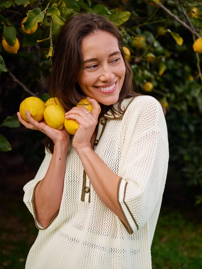 Frauenmodel trägt Strickshirt mit Polokragen und Knopfleiste curated by Anna Schürrle von Style Icon Collection aus Reine Baumwolle, Gerader-Schnitt, Grobstrick, 3/4-Arm, Nahaufnahme Oberkörper.