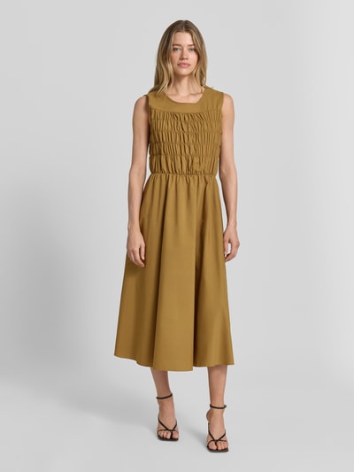 Frauenmodel trägt Midikleid mit V-Ausschnitt Modell 'NETTI' von Soyaconcept, Material-Mix mit Baumwoll-Anteil, Gerader-Schnitt, Rückenlänge bei Größe S 124 cm, Brustweite 43 cm, einfarbiges Design in warmem Braunton, glatte Textur, Ganzkörperansicht von vorne.