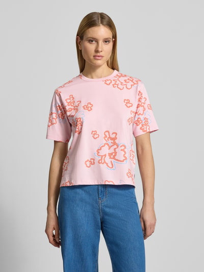 Frauenmodel trägt T-Shirt im Allover-Look mit Rundhalsausschnitt von JAKE*S STUDIO WOMAN aus reiner Baumwolle, Relaxed Fit, rosa mit orangen Blumenmotiven, glatte Textur, Ganzkörperansicht von vorne.
