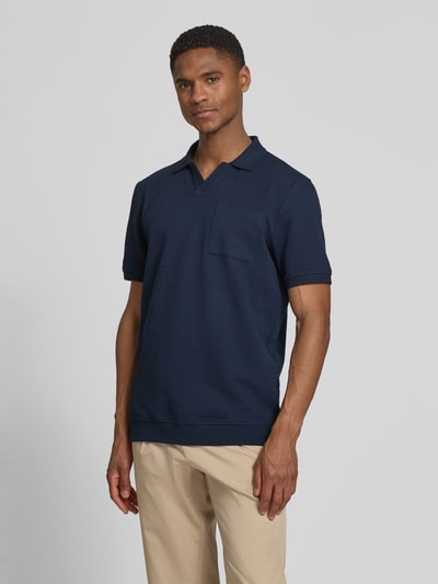 Männermodel trägt Regular Fit Poloshirt aus Baumwoll-Mix von s.Oliver RED LABEL in Dunkelblau, Seersucker-Struktur, Ganzkörperansicht von vorne.