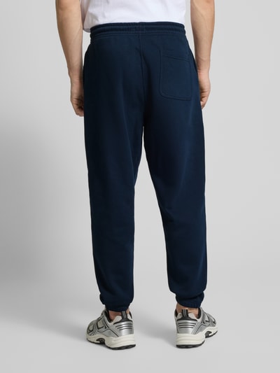 Männermodel trägt Regular Fit Sweatpants aus Baumwoll-Mix von Tommy Jeans in Optik: Unifarben, Gesäßtasche, Ganzkörperansicht Rückansicht.