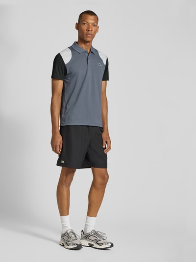 Männermodel trägt Regular Fit Sport-T-Shirt im Colorblock-Design von Lacoste, Grau mit Weiß und Schwarz, Ganzkörperansicht von vorne, Herren Sport-T-Shirt von Lacoste Sport.