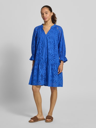Frauenmodel trägt Relaxed Fit Kleid in Knielänge mit floralem Allover-Lochstitching von Betty Barclay in leuchtendem Blau, reine Baumwolle, 3/4-Arm, Tunika-Ausschnitt, lockere Passform, florale Muster und leichte Textur, Ganzkörperansicht von vorne.