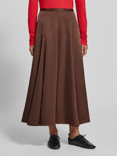Frauenmodel trägt Maxirock mit Strukturmuster von MYON in Braun, leichte A-Linie, glatte Satin-Struktur, Nahaufnahme Oberkörper.