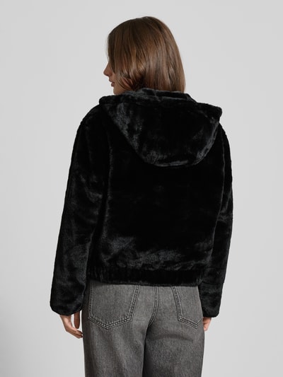 Kobiece model nosi Regular Fit Jacke in Webpelz-Optik od Tom Tailor Denim, czarna, jednolita, kaptur, długi rękaw, materiał futerkowy. Widok całej sylwetki od tyłu.