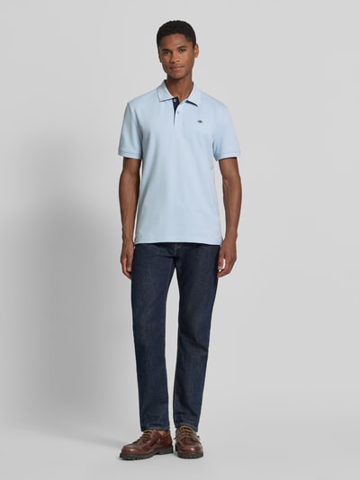 Männermodel trägt Regular Fit Poloshirt aus reiner Baumwolle von Tom Tailor in Hellblau, glatte Textur, Ganzkörperansicht von vorne.