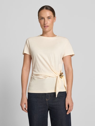 Frauenmodel trägt T-Shirt in Wickel-Optik mit Brosche von Christian Berg Woman Selection aus reiner Baumwolle in Creme, Regular Fit, Ganzkörperansicht von vorne.