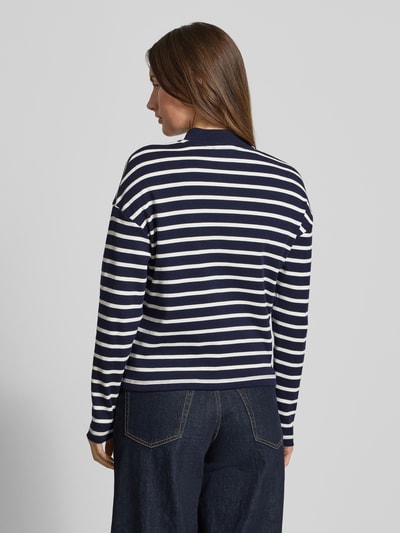 Frauenmodel trägt Ringel Polo Shirt mit Schmuckknopf von Christian Berg Woman, marineweiß gestreift, lockerer Schnitt, Ganzkörperansicht Rückansicht.