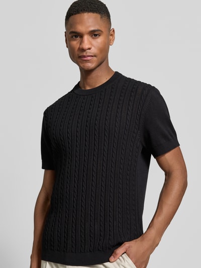 Männermodel trägt T-Shirt mit Zopfmuster von Lindbergh in Schwarz, reine Baumwolle, Strick-Optik, gerader Schnitt, Nahaufnahme Oberkörper